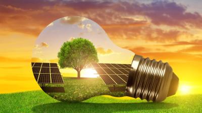 A light bulb with solar panels and a tree in the background.