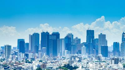 A city skyline with numerous modern skyscrapers and high-rise buildings under a blue sky with some clouds.