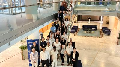 A group of people pose for a photo on a staircase and the marble floor of a spacious, modern lobby with seating and decorative elements.